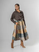 Falda midi de paño con estampa patchwork de inspiración escocesa, confeccionada en mezcla de lana. Presenta pinzas frontales, cintura elástica para mayor comodidad y un cinto desmontable a tono.