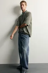 Jeans de denim de algodón en color azul con efecto desgastado, tiro medio y corte recto de ajuste holgado (loose fit). Cuenta con diseño clásico de cinco bolsillos y cierre frontal con cremallera y botón.