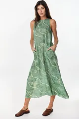 Vestido midi verde de lino italiano, con diseño sin mangas, cuello redondo y estampado de líneas onduladas punteadas. Cuenta con bolsillos laterales.
