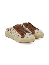 Zueco destalonado de estilo deportivo, confeccionado en cuero con pelo con estampado animal print tipo vaca en tonos blancos y marrones. Posee cordones marrones, detalles en cuero marrón y suela de plataforma de goma en tono tostado.