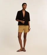 Bermuda roja de poliéster con cintura elástica, bolsillos laterales y cierre con cremallera y botones.