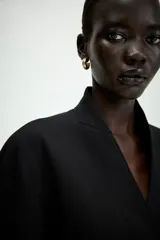 Blazer negro de corte entallado con cuello solapa, manga larga y cierre frontal cruzado con dos botones.