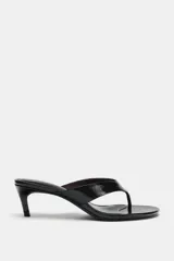 Sandalia de piel con acabado charol en color negro, diseño tipo thong con separación para el dedo, tacón fino medio y punta redonda.