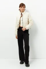 Campera puffer corta color beige de nylon, con cuello alto, cierre frontal y bolsillos laterales con cierre.