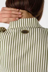 Camisa blanca de viscosa con cuello camisero, mangas largas abullonadas con puños elásticos y cierre frontal con botones. Presenta bordados negros con motivos florales en las mangas.