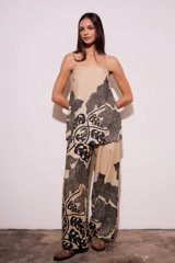 Pantalón de lino color beige con estampado de hojas negras, corte flare y tiro alto.