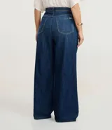 Pantalón de jean modelo wide leg, de tiro medio y corte amplio desde la cadera hasta el ruedo. Presenta cierre frontal con botón, bolsillos laterales y traseros, y trabillas en la cintura.