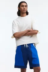 Short de baño y deportivo confeccionado en nylon, de corte holgado. Presenta un diseño de bloques de color en tonos azul, azul marino y blanco. Cuenta con cintura elástica con cordón ajustable blanco, bolsillos laterales y aberturas en los costados del ruedo. Incluye suspensor interno de malla.
