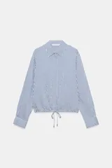 Camisa de cuello solapa y manga larga a rayas azules y blancas, con bajo ajustable mediante cordones y cierre frontal con botones ocultos.