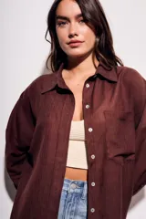 Camisa marrón de tencel y poliéster, corte oversize, manga larga y cierre con botones.
