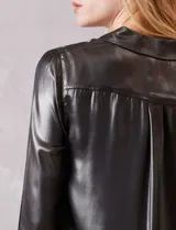 Camisa de manga larga con acabado satinado y efecto metalizado en color gris oscuro. Presenta cuello camisero clásico, cierre frontal con botones forrados y puños estructurados.