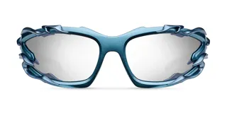 Lentes de sol con montura envolvente de color azul metalizado, con detalles decorativos de líneas orgánicas en los laterales. Cuentan con lentes de nylon en color gris y protección UV400.