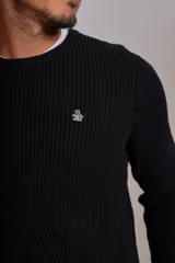 Sweater de punto grueso con cuello redondo, manga larga y puños acanalados. Presenta un pequeño logo bordado en el pecho.