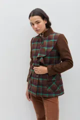 Chaqueta de corte entallado con cuerpo en tejido tartán de lana en tonos tierra y verde, y mangas largas en color marrón liso. Presenta cuello mao con volado frontal, cierre frontal y bolsillos con solapa.