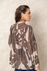 Camisa oversize con estampado abstracto en tonos marrones y beige, cuello mao y cierre frontal con botones. Presenta mangas largas anchas con puños abotonados y un corte holgado.