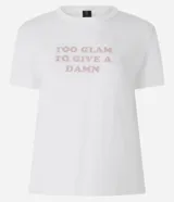 Remera de algodón blanca con cuello redondo y mangas cortas. Presenta una estampa frontal con la frase 'Too glam to give a damn' decorada con strass rosados y detalles de pliegues en los hombros.