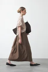 Falda larga plisada color marrón, de silueta amplia y caída fluida.