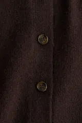 Saco de punto suave con cuello camisero y cierre frontal de botones. Presenta mangas cortas y terminaciones acanaladas en puños y ruedo.