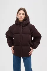 Campera puffer de color marrón oscuro, con diseño capitoneado, cierre frontal, capucha ajustable y bolsillos laterales con cierre.