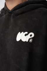 Buzo canguro oversize de algodón frisa premium con efecto lavado en color negro. Presenta capucha, bolsillo frontal tipo canguro y estampa blanca en el pecho.