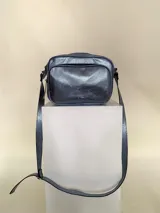Bandolera rectangular de cuero azul metalizado con correa larga regulable. Cuenta con un bolsillo frontal con fuelle y un bolsillo trasero con cierre.