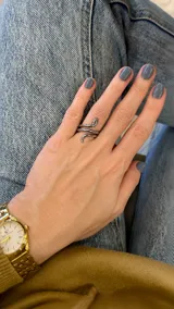 Anillo de acero plateado con diseño en forma de serpiente enrollada alrededor del dedo.