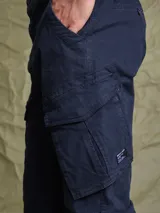 Pantalón cargo color azul marino, confeccionado en sarga de algodón con spandex. Presenta bolsillos laterales tipo cargo con solapa y etiqueta de la marca Benson & Thomas.