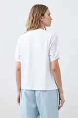 Remera blanca de algodón con mangas cortas de broderie, cuello redondo y corte recto.