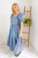 Vestido largo celeste con escote cuadrado, mangas abullonadas cortas y corte imperio con falda escalonada.