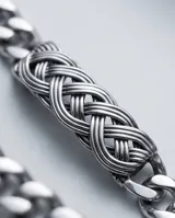 Pulsera de acero inoxidable con eslabones de cadena y un detalle central de diseño trenzado tipo nudo celta.
