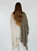 Ruana de punto bicolor, con un lado marrón y otro lado beige con detalle de bordado floral y flecos en los bordes inferiores.