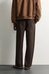 Pantalón chino de corte regular, color marrón oscuro, con cierre frontal de cremallera y botón, bolsillos laterales y bolsillos traseros de vivo.