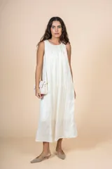 Vestido midi color crema, de corte recto y cuello redondo. Presenta bolsillos laterales y diseño sin mangas.