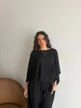 Conjunto de dos piezas de lanilla en color gris melange, compuesto por una blusa de corte amplio con mangas murciélago y escote bote, y un pantalón recto con bolsillos laterales.