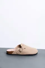 Sandalias cerradas tipo zueco color beige, con tira ajustable y hebilla metálica dorada. Plantilla anatómica y suela de corcho con base de goma.