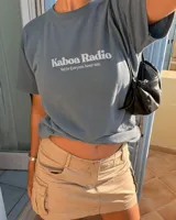 Remera oversize negra con diseño gráfico en la espalda que incluye la inscripción "Kaboa Radio" y un personaje ilustrado, de corte amplio y mangas cortas.