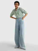 Camisa de corte amplio, a rayas verticales verdes y blancas, con cuello inglés, cierre frontal con botones y logo de Tommy Hilfiger bordado en el puño.