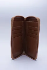 Billetera chica de cuero negro con textura tipo cocodrilo, cierre exterior, bolsillo para monedas con cierre en la parte trasera, múltiples ranuras para tarjetas y billetes, y forro rojo.