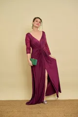 Vestido largo bordó de fiesta, con escote en V pronunciado, nudo drapeado en la cintura y tajo frontal. Las mangas son tres cuartos en tul translúcido con detalles sutiles.