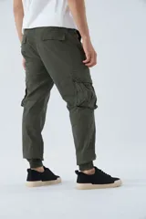 Pantalón cargo color beige, corte slim, con bolsillos laterales con botón, cierre con botón y puños en los tobillos.