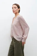 Blusa color beige con textura de lunares en relieve, escote en V y mangas largas con puños elásticos.
