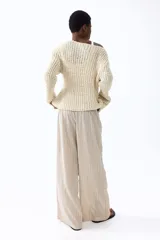 Pantalón amplio de punto, tiro alto, con cintura elástica y cordón ajustable. Presenta un diseño de rayas verticales en tonos beige y marrón claro.