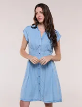 Vestido camisero corto Zac & Rachel de denim liviano, con cuello camisero clásico, escote en V y abotonadura frontal completa. Presenta mangas cortas, cintura entallada con pinzas verticales y falda de corte evasé con suaves pliegues.
