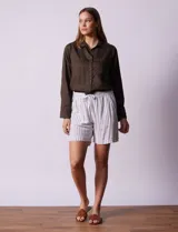 Short blanco con rayas verticales grises, de lino y rayón. Tiene pretina ancha elastizada con lazo de ajuste y bolsillos delanteros.