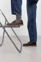 Mocasín de cuero vacuno en color marrón, con diseño bitono que combina texturas lisas y con grabado tipo cocodrilo en el empeine. Cuenta con detalle de estribo clásico y suela plana con vira en contraste.