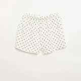 Short de punto gofrado color blanco con estampado de lunares negros y detalle de botones decorativos en la parte frontal.
