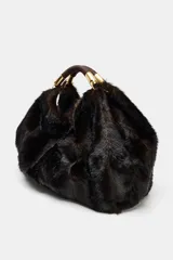 Maxi bolso de mano con acabado de pelo sintético en color marrón oscuro. Presenta un diseño estructurado con doble asa de mano reforzada y detalles metálicos dorados en las uniones. Cuenta con cierre mediante botón imantado y forro interior con bolsillo con cremallera.