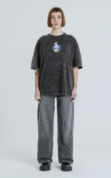 Remera de algodón premium color gris oscuro con efecto nevado (acid wash), corte oversize y manga corta. Estampa trasera con el personaje de Mickey Mouse vestido de chef rodeado de llamas y utensilios de cocina, con texto en inglés y chino.