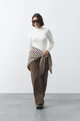 Polera de tejido de punto color celeste, con cuello alto y textura de pequeños puntos en relieve formando una cuadrícula en el frente y las mangas. De corte ajustado y manga larga.