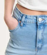 Short de jean celeste, corte hotpants, de cintura alta, con bolsillos delanteros y traseros, cierre con botón y cremallera, y ruedo doblado.